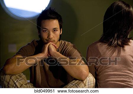 Stock Image - Asian couple facing opposite directions. Fotosearch
