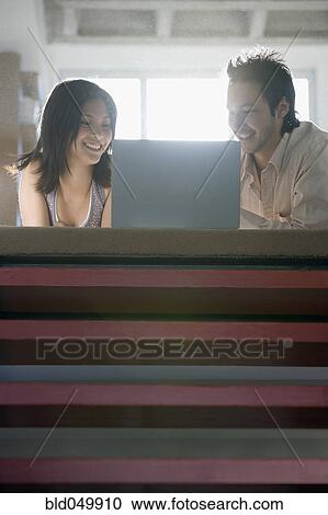 Asian couple looking at laptop View Large Photo Image Stock Image - Asian couple looking at laptop. Fotosearch