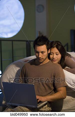 Stock Image - Asian couple looking at laptop. Fotosearch