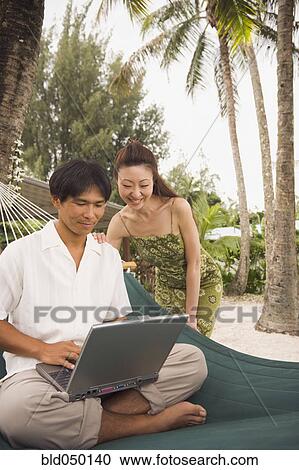 Stock Image - Asian couple looking at laptop. Fotosearch