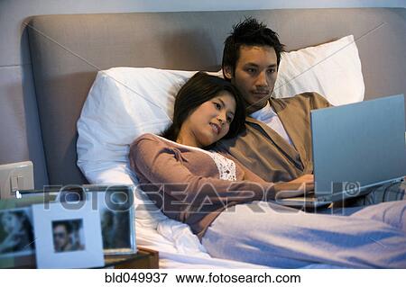 Stock Photo - Asian couple looking at laptop. Fotosearch
