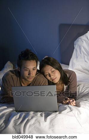 Stock Photo - Asian couple looking at laptop. Fotosearch