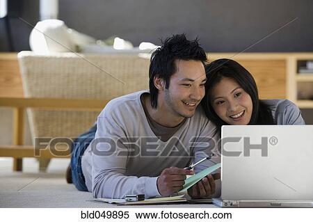 Asian couple looking at laptop View Large Photo Image Stock Photography - Asian couple looking at laptop. Fotosearch