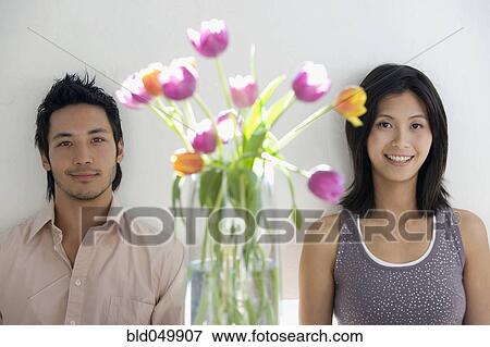 Stock Photo - Asian couple next to flowers in vase. Fotosearch