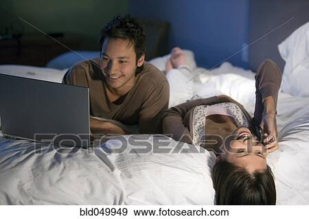 Stock Photo - Asian couple relaxing on bed. Fotosearch