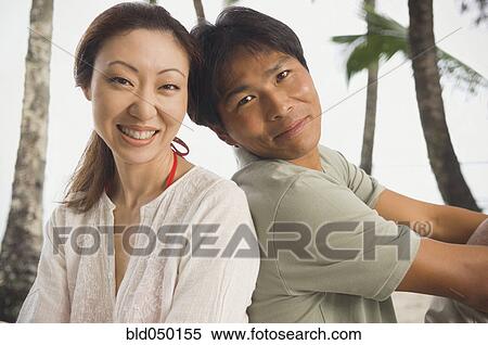 Asian couple sitting back to back View Large Photo Image Stock Photography - Asian couple sitting back to back. Fotosearch