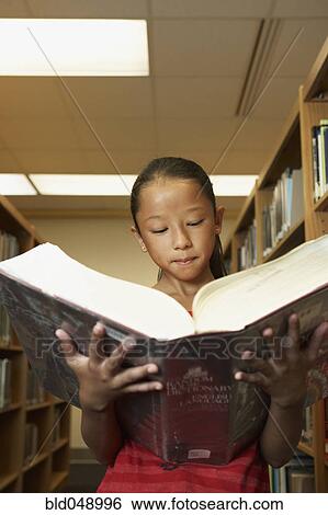 Stock Photograph - Asian girl reading library dictionary. Fotosearch