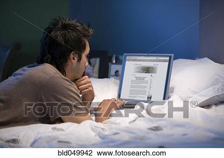 Stock Image - Asian man looking at laptop. Fotosearch