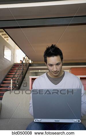 Stock Photo - Asian man looking at laptop. Fotosearch
