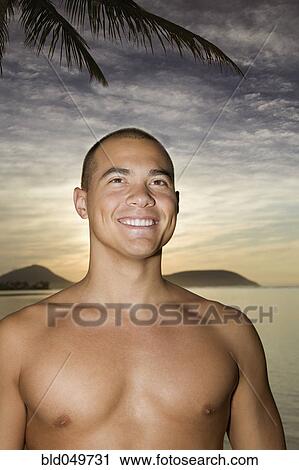 Stock Image - Asian man next to water at sunset. Fotosearch