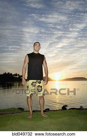 Asian man next to water at sunset View Large Photo Image Stock Image - Asian man next to water at sunset. Fotosearch