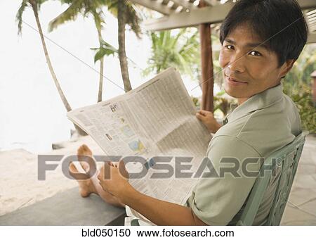 Stock Image - Asian man reading newspaper. Fotosearch