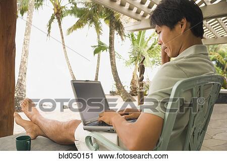 Stock Image - Asian man typing on laptop. Fotosearch
