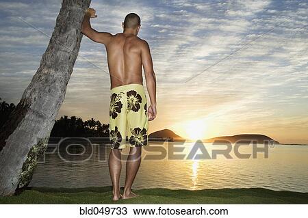 Stock Image - Asian man watching sunset. Fotosearch