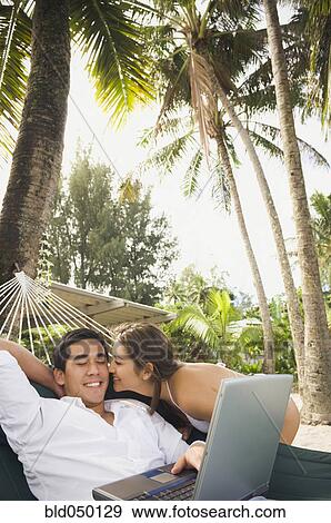 Stock Photo - Asian man with laptop in hammock. Fotosearch