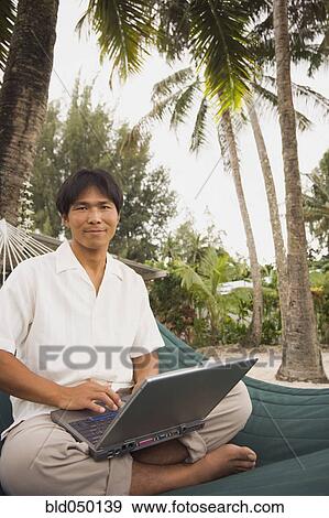 Asian man with laptop in hammock View Large Photo Image Stock Photo - Asian man with laptop in hammock. Fotosearch