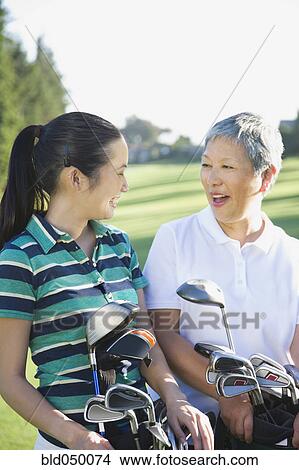 Asian mother and adult daughter holding golf bags View Large Photo Image Picture - Asian mother and adult daughter holding golf bags. Fotosearch