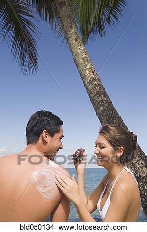 Asian woman applying sunscreen to boyfriend View Large Photo Image Picture - Asian woman applying sunscreen to boyfriend. Fotosearch