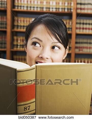 Stock Photo - Asian woman holding library reference book. Fotosearch