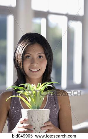Stock Photography - Asian woman holding potted plant. Fotosearch