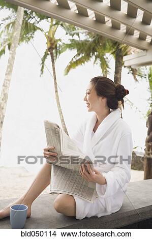 Asian woman in bathrobe reading newspaper View Large Photo Image Picture - Asian woman in bathrobe reading newspaper. Fotosearch