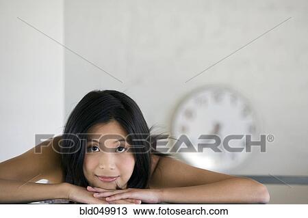 Stock Image - Asian woman resting chin on hands. Fotosearch