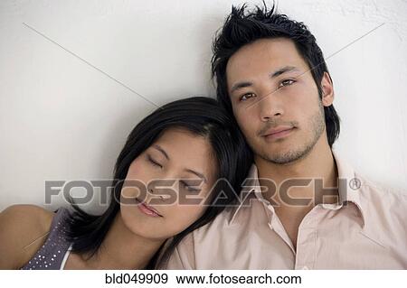 Stock Photo - Asian woman resting on boyfriend’s shoulder. Fotosearch