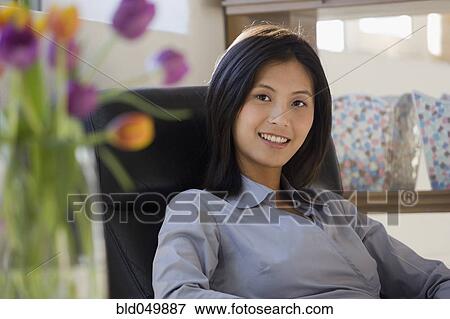 Stock Photo - Asian woman sitting in chair. Fotosearch