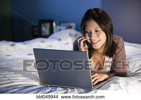Picture - Asian woman talking on cell phone. Fotosearch