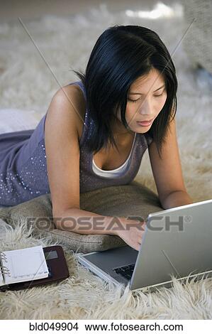 Picture - Asian woman using laptop on floor. Fotosearch