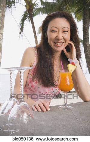 Asian woman with cocktail at beach bar View Large Photo Image Stock Photograph - Asian woman with cocktail at beach bar. Fotosearch