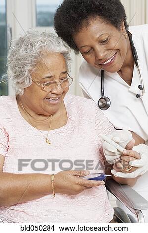 Picture - Doctor testing African American woman’s blood sugar. Fotosearch