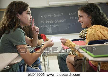 Stock Photography - Girls passing note in class. Fotosearch
