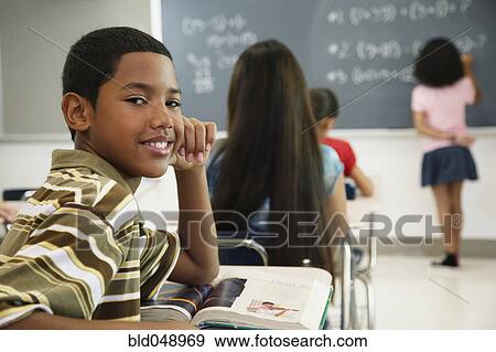 Stock Photo - Hispanic boy at desk in classroom. Fotosearch