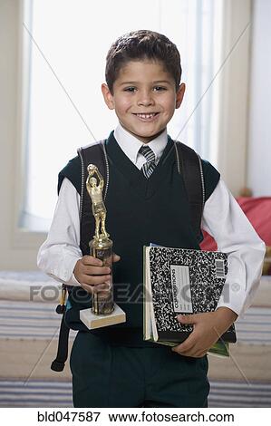 Hispanic boy holding trophy and school books View Large Photo Image Stock Photo - Hispanic boy holding trophy and school books. Fotosearch
