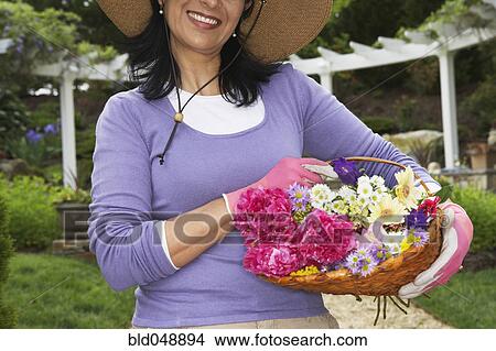 Picture - Hispanic woman holding basket of flowers. Fotosearch