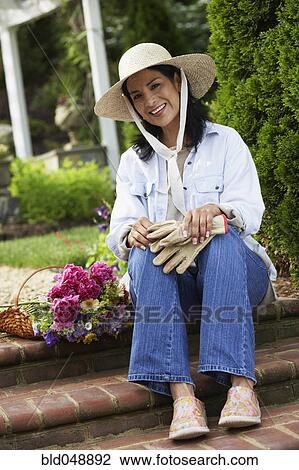 Stock Image - Hispanic woman next to cut flowers. Fotosearch