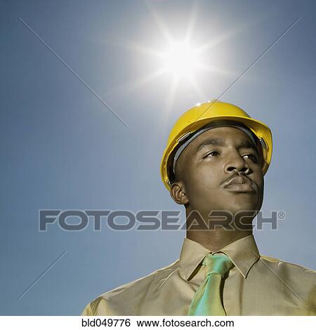 Low angle view of African American man wearing hard hat View Large Photo Image Stock Photograph - Low angle view of African American man wearing hard hat. Fotosearch