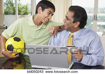 Stock Image - Middle Eastern father and son shopping online. Fotosearch