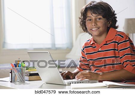 Stock Photo - Mixed Race boy typing on laptop. Fotosearch