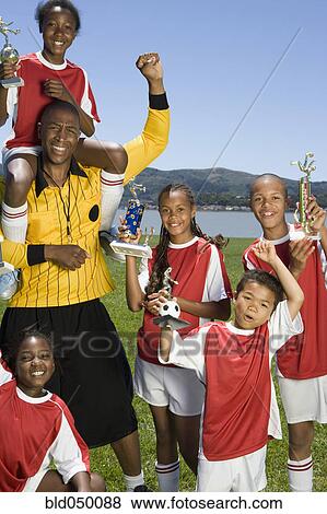 Stock Photo - Multi-ethnic children holding soccer trophies. Fotosearch