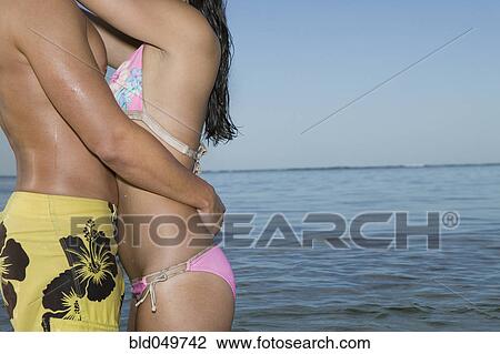 Multi-ethnic couple in bathing suits hugging View Large Photo Image Stock Image - Multi-ethnic couple in bathing suits hugging. Fotosearch