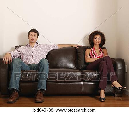 Multi-ethnic couple sitting on sofa View Large Photo Image Stock Image - Multi-ethnic couple sitting on sofa. Fotosearch