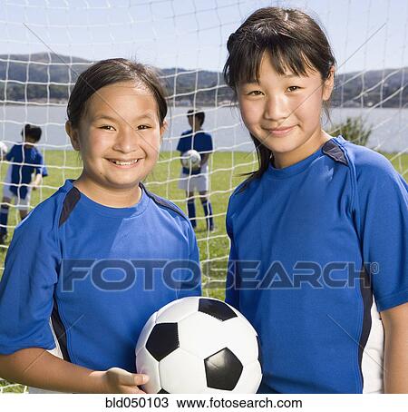 Stock Image - Multi-ethnic girls with soccer ball. Fotosearch