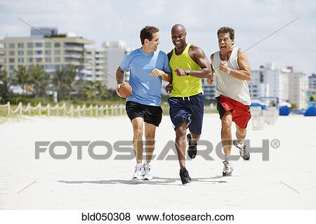 Multi-ethnic men running in beach View Large Photo Image Stock Photo - Multi-ethnic men running in beach. Fotosearch