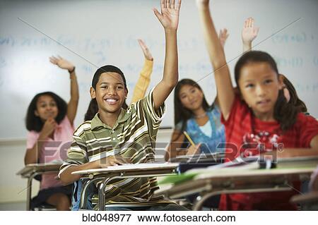 Stock Photo - Multi-ethnic students raising hands in class. Fotosearch