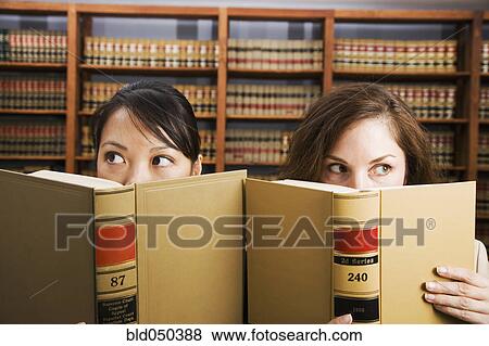 Multi-ethnic women holding library reference book View Large Photo Image Stock Photo - Multi-ethnic women holding library reference book. Fotosearch