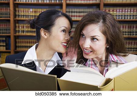 Multi-ethnic women whispering in law library View Large Photo Image Stock Photography - Multi-ethnic women whispering in law library . Fotosearch