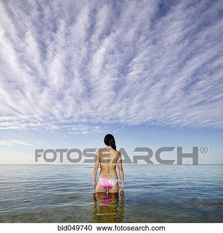 Stock Image - Pacific Islander woman standing in ocean. Fotosearch