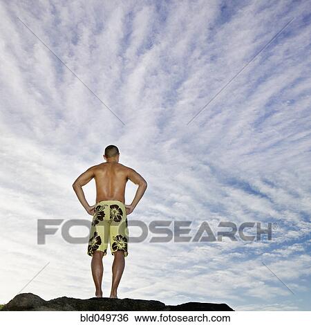Stock Photograph - Rear view of Asian man with hands on hips. Fotosearch